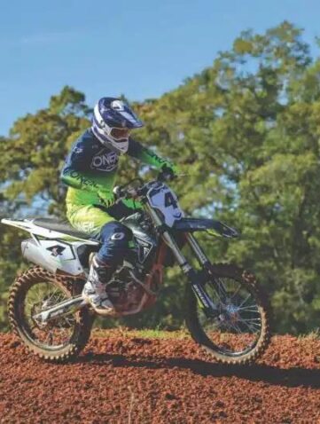 Rider en tenue O'Neal vert fluo en action sur un terrain de motocross en terre rouge