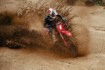 Pilote de motocross en virage dans une gerbe de terre, masque 100% Ultra Hydro
